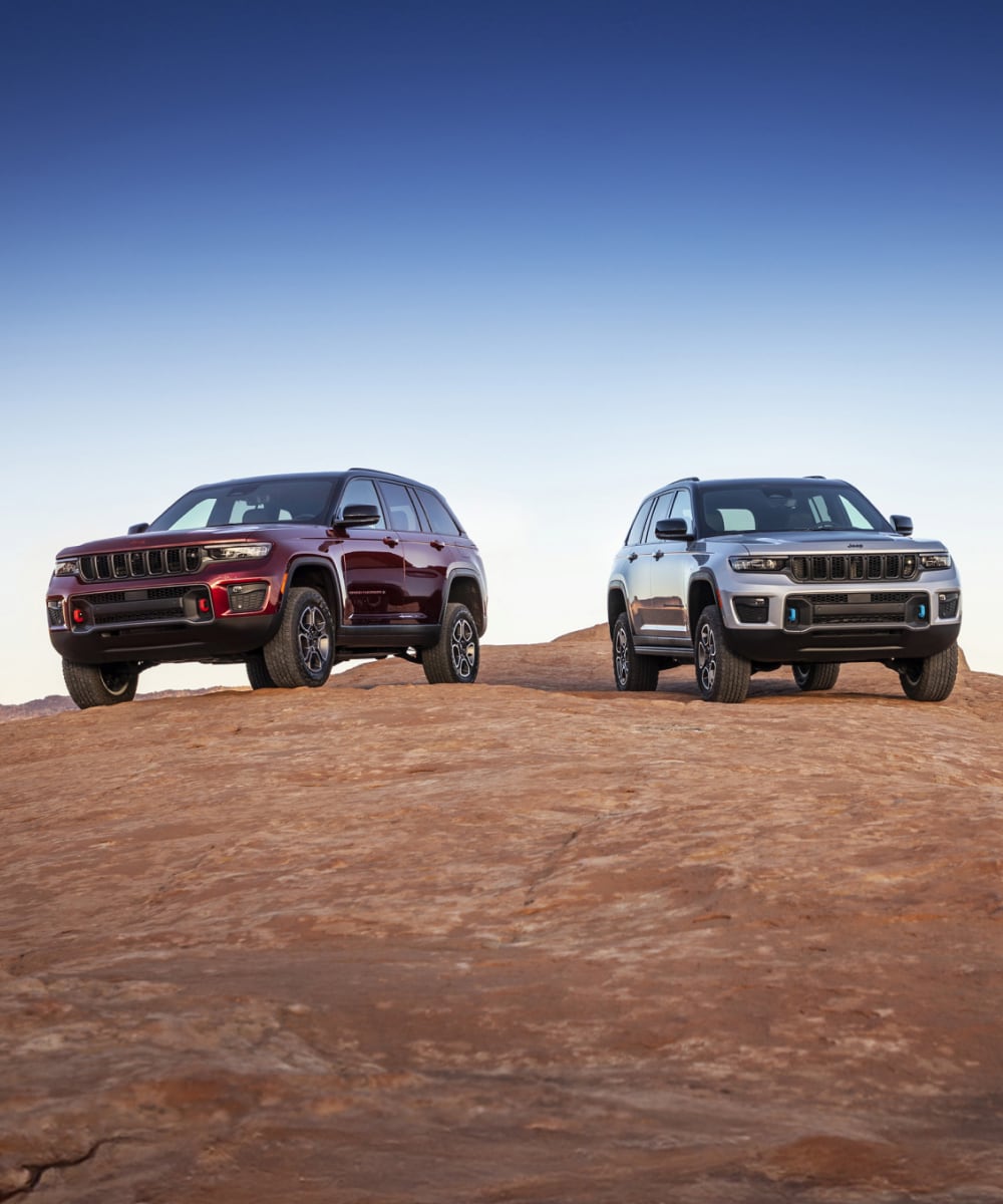 Front angled view of two Jeep Grand Cherokee on top of mountain