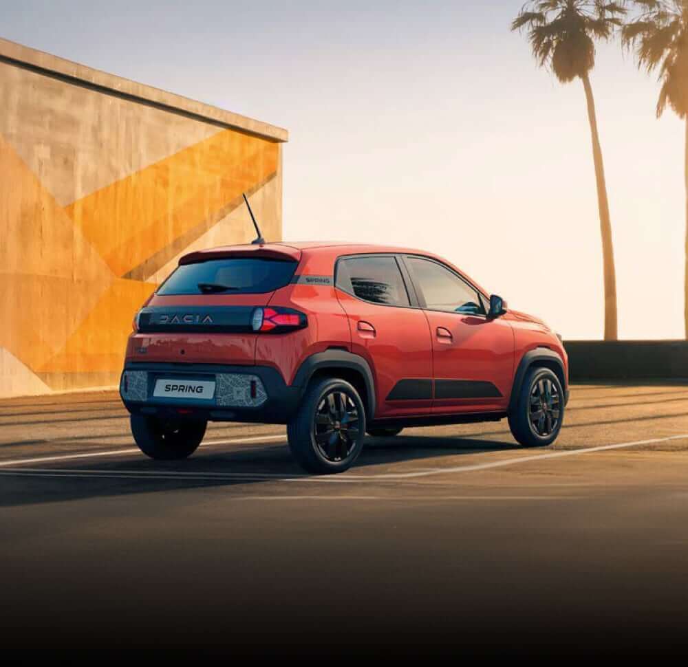 Rear angled view of Dacia Spring with sunset background